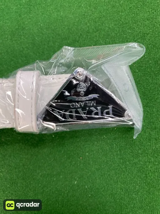P-shaped silver buckle with white belt on black background